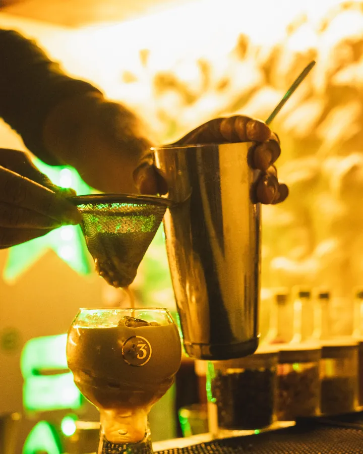 Bartender coando um drinque no balcão do Bra Bra Amauri