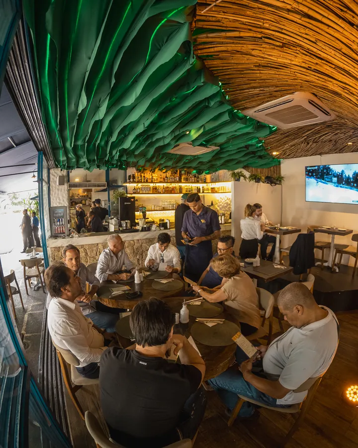A full room at Bra Bra Amauri: a group at the table and the waiter taking the order, with the bar busy behind